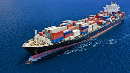 Aerial drone photo of industrial colourful vessel carrying heavy truck size containers cruising the Mediterranean deep blue sea