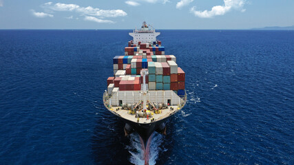 Fototapeta premium Aerial drone photo of industrial colourful vessel carrying heavy truck size containers cruising the Mediterranean deep blue sea