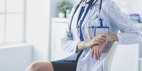 Portrait of young female doctor sitting at desk in hospital