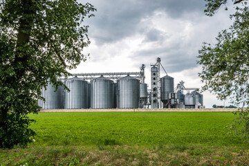 Modern Granary elevator and seed cleaning line. Silver silos on agro-processing and manufacturing plant for processing drying cleaning and storage of agricultural products, flour, cereals and grain.