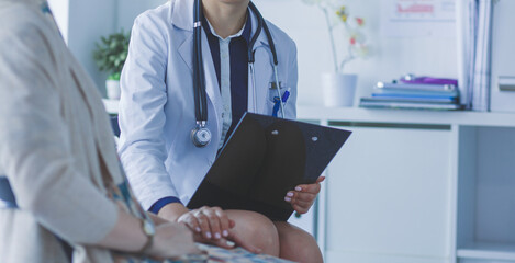 Doctor and patient discussing something while sitting at the table . Medicine and health care concept