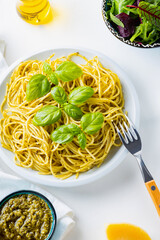 Spaghetti with pesto sauce and basil on a white background. Pasta with sauce pesto and ingredients. Traditional Italian cuisine. Food styling