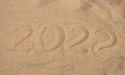 Fototapeta na wymiar The numbers 2022 in the sand. The concept of the New Year 2022. Summer holidays and sea trips