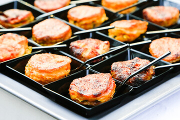 fingerfood closeup. small backed oriental snacks on square black plates with tiny spoons. Catering layout. Gourmet food degustation. Menu concept picture. Healthy dieting. corporate party snacks