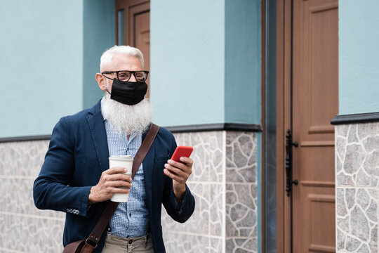 Senior hipster business man walking to work drinking coffee while wearing safety mask - Focus on face - Powered by Adobe