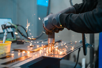 a woman working in the modern metal production and processing industry welds the product and prepares it for a cnc machine