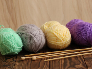 Colorful knitting yarn and needles on wooden background. Handicraft concept
