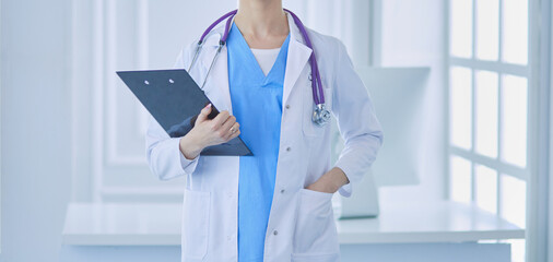 Smiling female doctor with a folder in uniform standing