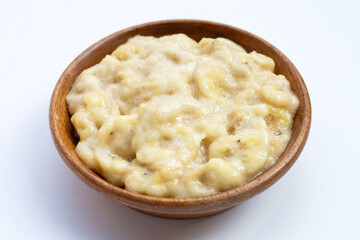 Mashed Bananas in wooden bowl on white background.