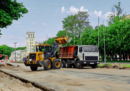 the excavator loads sand into the body of the KAMAZ truck