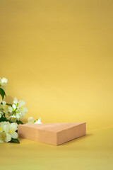 Triangular podium for the demonstration of cosmetics, products on a beige background and jasmine