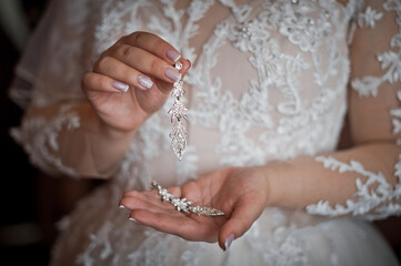 The bride is holding beautiful earrings in her hands 3168.