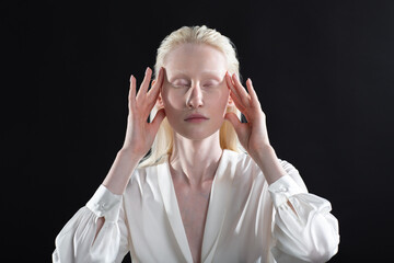 Young blonde albino woman doing face building facial gymnastics self massage and rejuvenating exercises on black background.