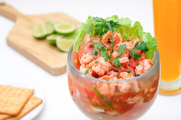 Cóctel de camarones en ceviche con bebida, limon y galletas saladas.