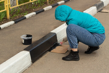 The girl paints the border. Saturday clean-up in Russia.