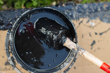 Fototapeta na wymiar Paint brush in a bucket. Black paint for wood.
