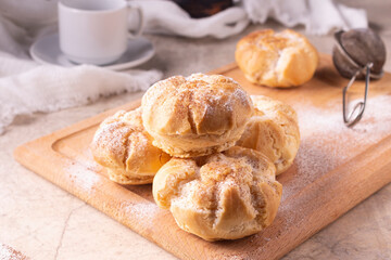 Profiteroles, a sieve with powdered sugar, breakfast cups.