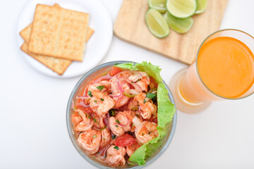 Cóctel de camarones en ceviche con bebida, limon y galletas saladas.