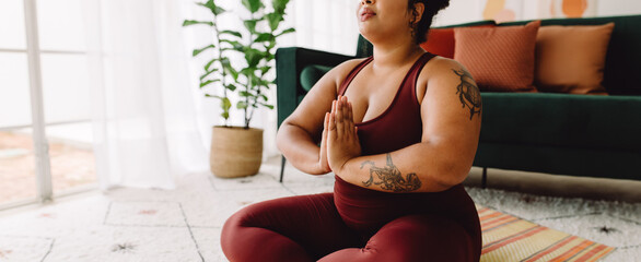 Plus size female practicing yoga meditation at home