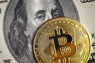 Bitcoin vs US dollar, gold bit coin on 100 dollar bill close-up