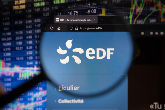 EDF company logo on a website with blurry stock market developments in the background, seen on a computer screen through a magnifying glass