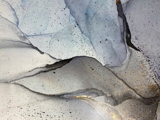 Abstract blue background with gold. Modern abstraction with beautiful smudges, stains and spots made with alcohol ink and golden paint. Blue fluid texture resembles water, smoke, watercolor, aquarelle