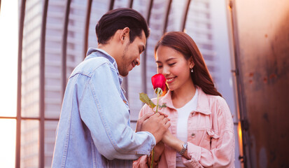 a beautiful young couple holding red roses for each other