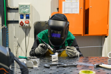 A woman employed in a modern factory for the production and processing of metals in a work uniform...