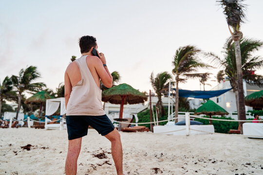 Portrait Of Unrecognizable Caucasian Man Talking On The Phone On The Beach At Sunset In Cancun At A Beach Club