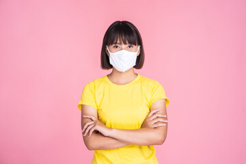 Asian woman wearing white face mask pm2.5 panic safety protection prevention against coronavirus covid-19 dust pollution illness and sickness, portrait female looking camera pink isolated background