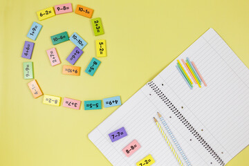 Open notebook, pencils and mathematical examples on yellow background. Back to school, fun learning...