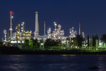 Obraz na płótnie Canvas Oil refinery river side with boat supply tank