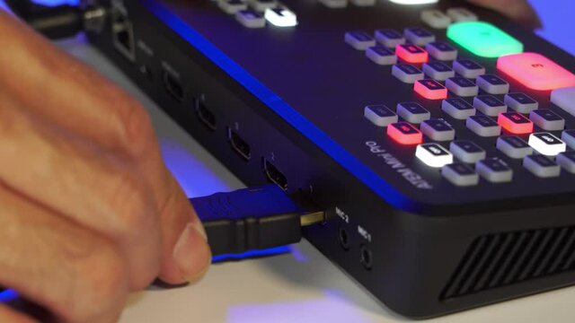 Close-up shot of connecting an HDMI cable to a video switcher in preparation for a live broadcast or video production shoot.