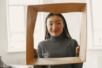 Asian young woman looking through cardbox in new flat