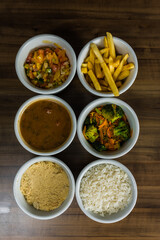 Porções de comida brasileira com feijão, arroz, farofa, batata frita e vinagrete.