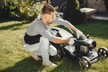 Fototapeta premium Man repairs lawnmover in a backyard
