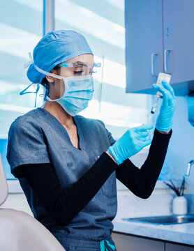 Nurse in face mask and shield preparing Covid-19 vaccination