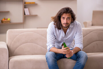 Young man drinking alcohol at home