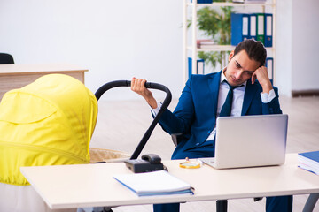 Young male employee looking after kid at workplace
