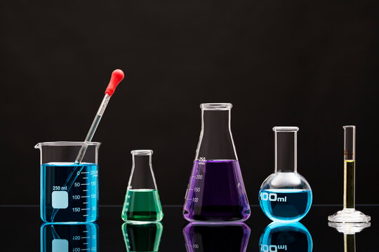 Laboratory glassware with liquids against black background