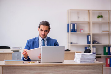 Young male employee and too much work in the office