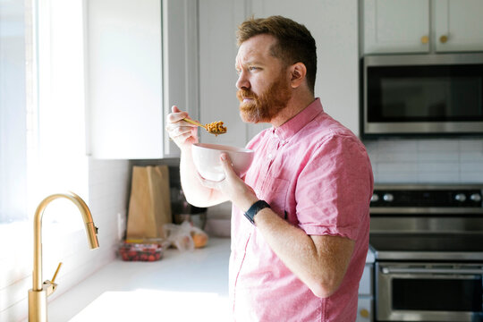 Man Eating Cereal In Kitchen