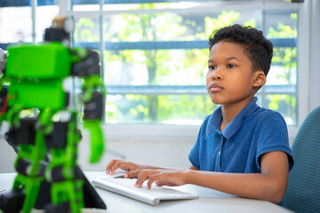 An african american boy is setting robot kit in robotic classroom.