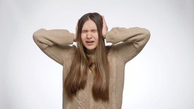 Young girl feeling annoyed of loud noise and suffering from headache closing ears with hands