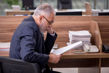 Old male employee sitting in the office