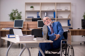 Old businessman employee in wheel-chair working in the office