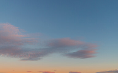 Pink clouds on blue-orange sky at sunset time.