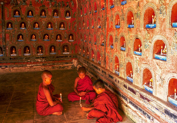 Myanmar, Shan State, Inle Lake, Novice Buddhist monks lighting candles in Shwe Yan Pyay Monastery