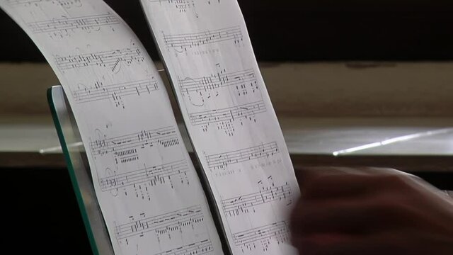 Female Hands placing Piano Sheet Music on Sheet Music Holder. Close Up.  