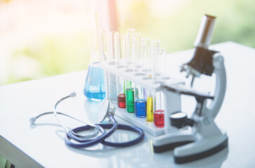 Fototapeta premium Microscope and colorful test tubes on table in Laboratory. Science chemistry concept. Blue tone